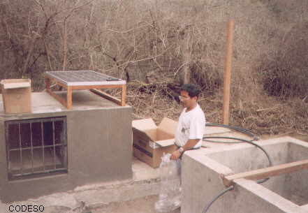 Instalación de bombeo de agua dulce con sistema solar en la isla de la Plata en ManabíA la derecha se ve el pozo profundo, al frente el panel fotovoltaico y la caseta de equipo